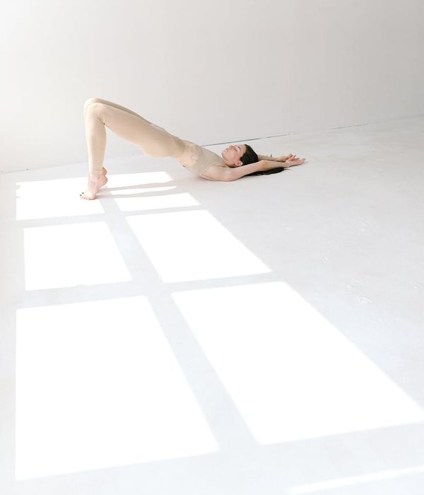 Woman in a calm yoga pose in a studio with pink light.